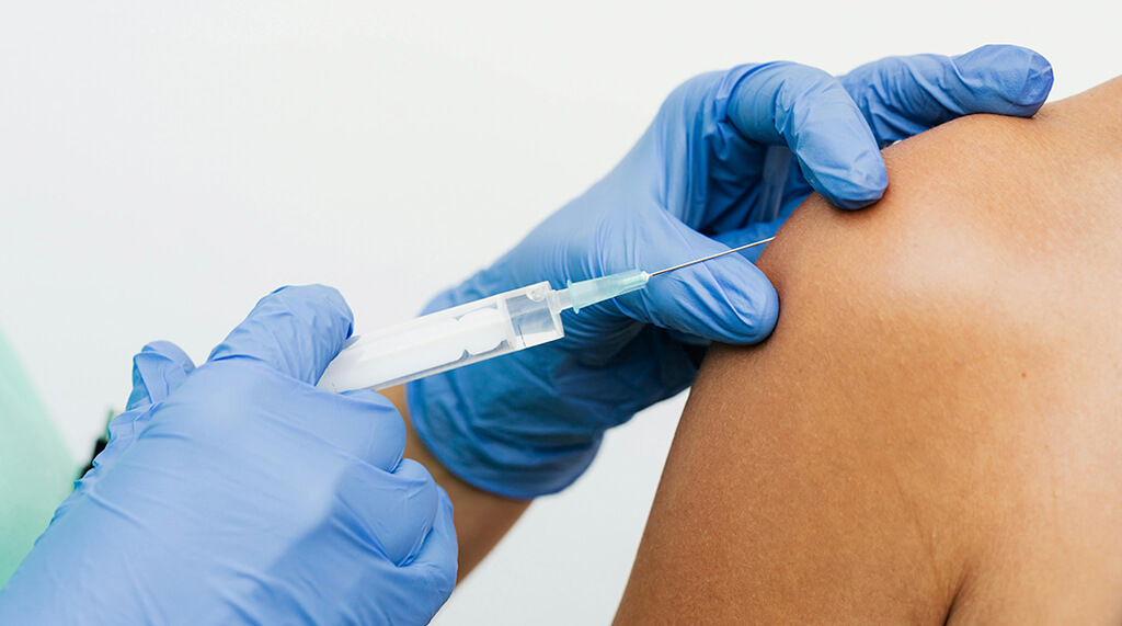 hands of medical person wearing blue nitrile gloves and giving injection