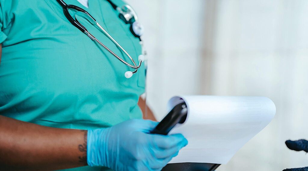 a medical professional wearing blue nitrile gloves and holding a clip board